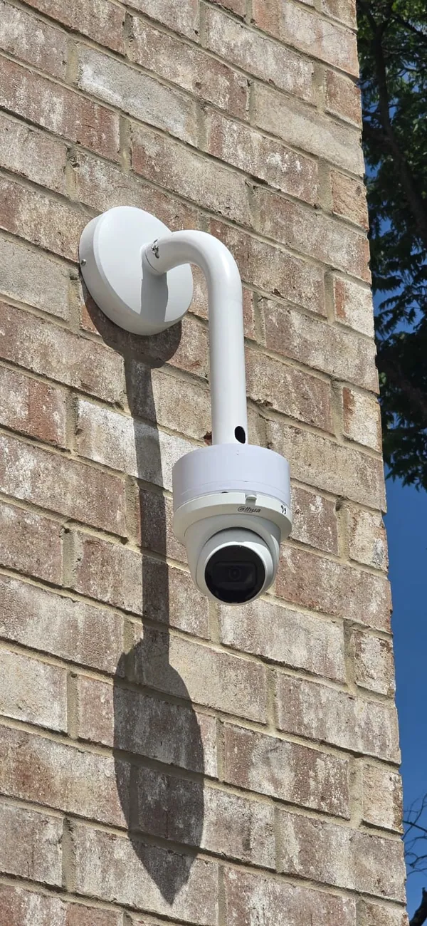 Dome camera on a gooseneck arm on brick